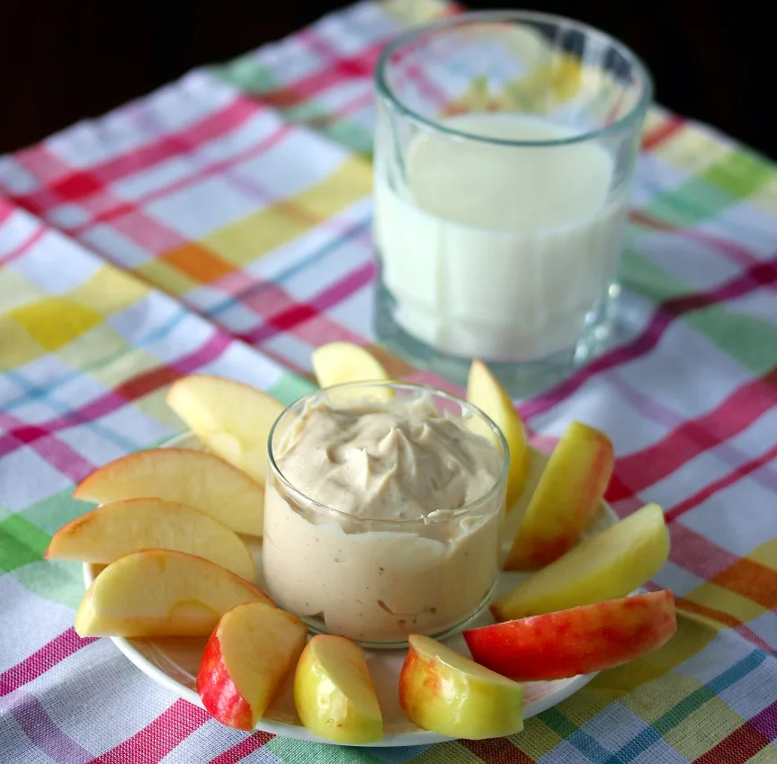 peanut butter yogurt dip plated with apple slices and served with a glass of milk