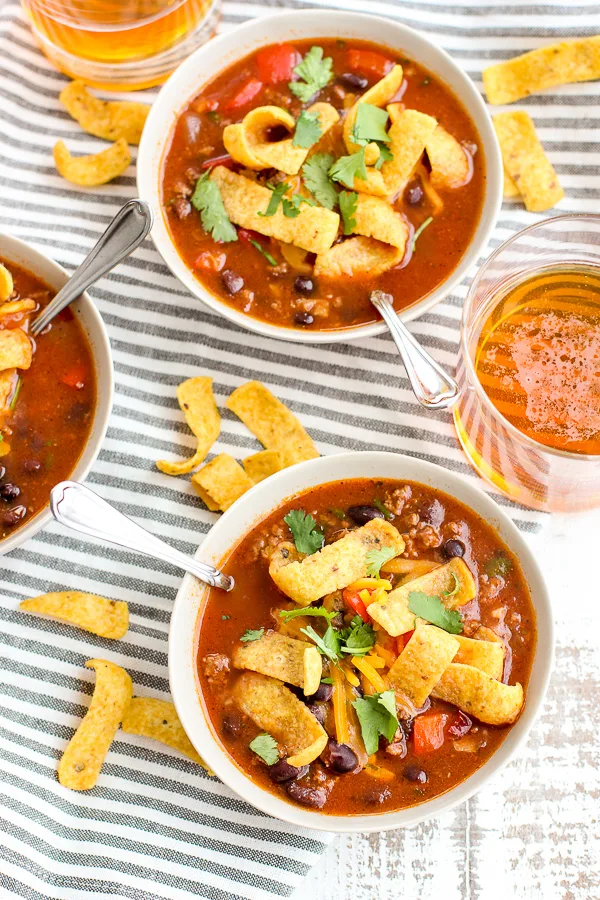 Beef Enchilada Soup topped with fritos and served with beer.