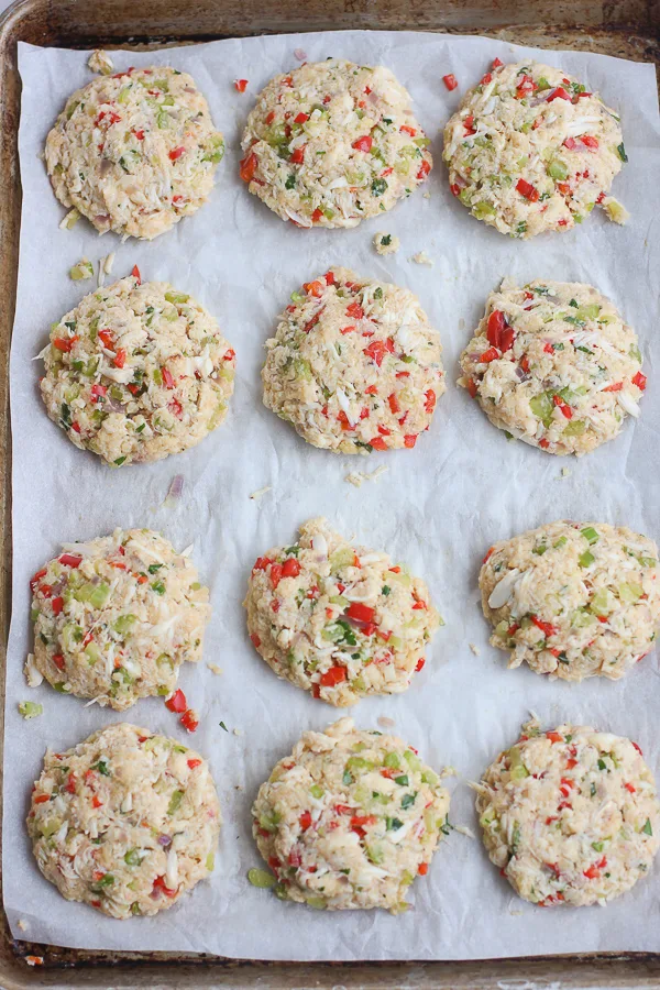 Mini crab cakes formed and place on a sheet pan lined with parchment paper and ready to fry.