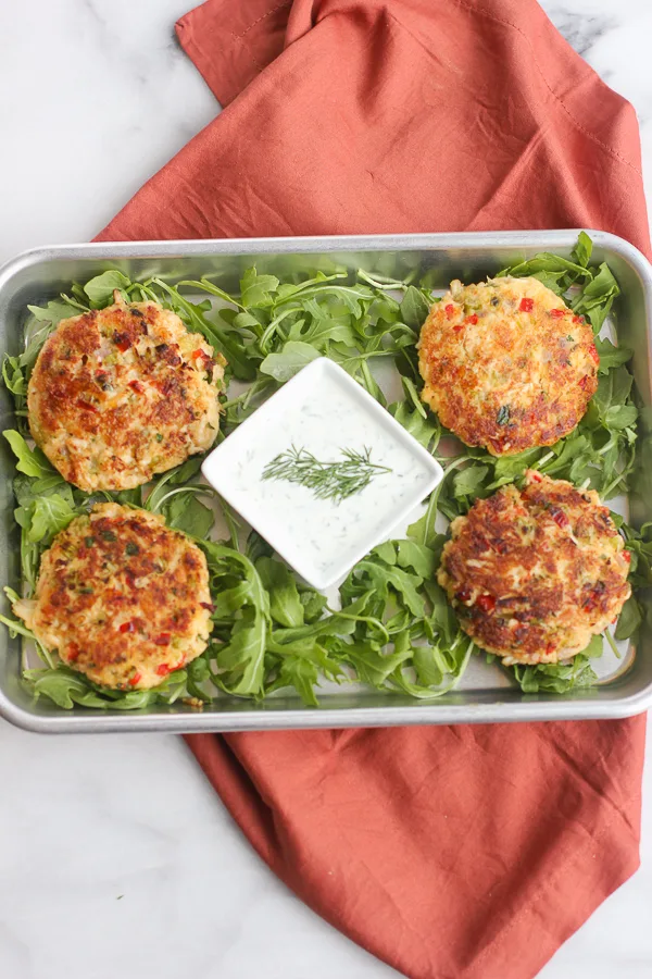 plated crab cakes with yogurt dill sauce over a bed of arugula