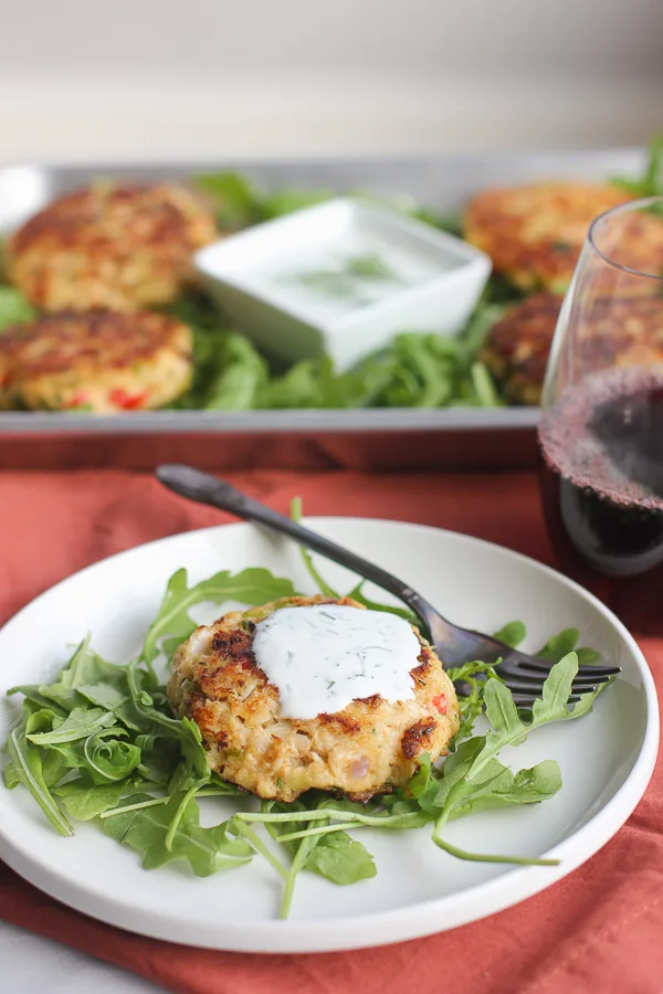 Plated crab cake over arugula and topped with the yogurt dill sauce