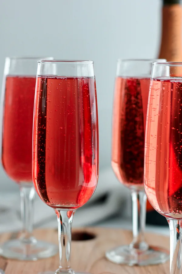 Close up photo Cranberry-Raspberry Champagne Cocktails served in champagne flutes