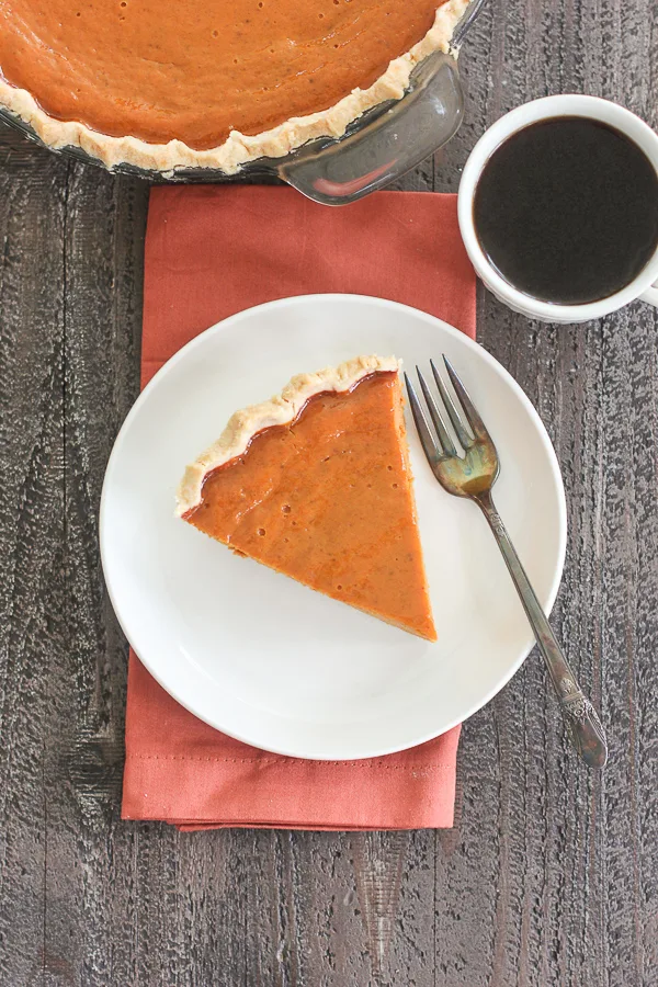 Overhead shot of a slice of maple pumpkin pie served with coffee
