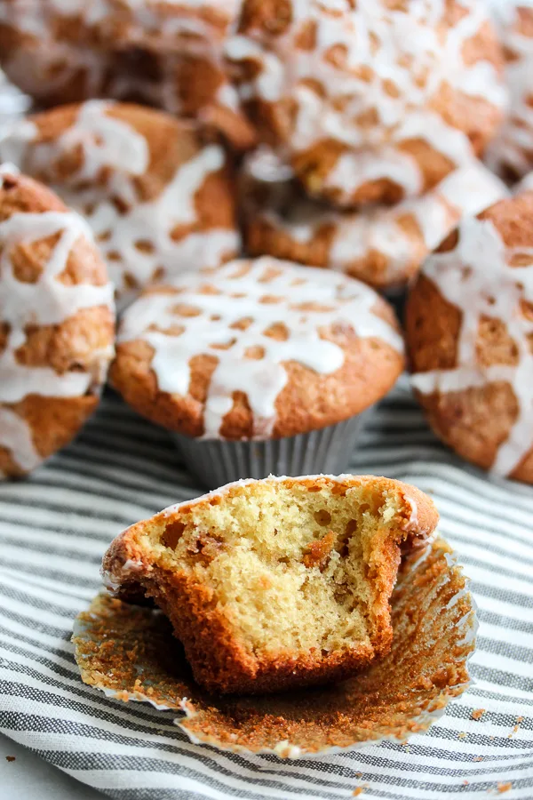 Cinnamon Roll Muffins in the background with a muffin in the from with a bite taken out of it