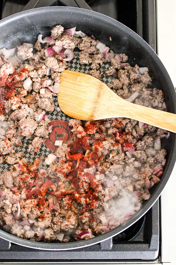 Sautéing the ground beef in a skillet with the spices added