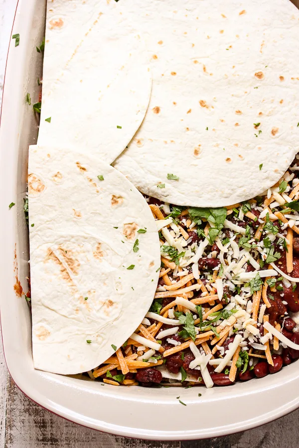 Demonstrating how to assemble the enchilada casserole in the baking dish