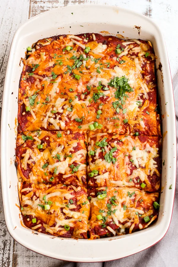 Finished Enchilada Casserole in the baking dish with half of it cut into pieces for serving