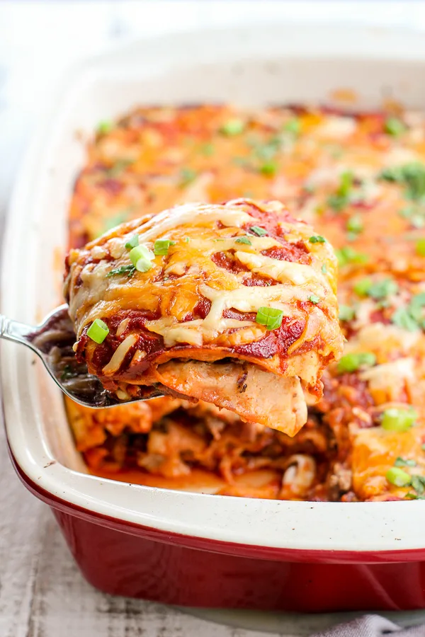 Lifting a piece of the Enchilada Casserole out of the baking dish with a spatula