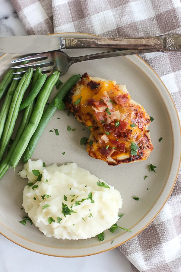 Overhead photo of the finished cheddar cheese chicken thigh with bacon served with mashed potatoes and green beans