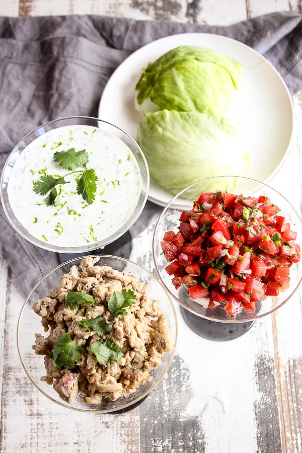 Chicken mixture, pico de gallo, sour cream sauce and iceberg lettuce in serving bowls ready to eat