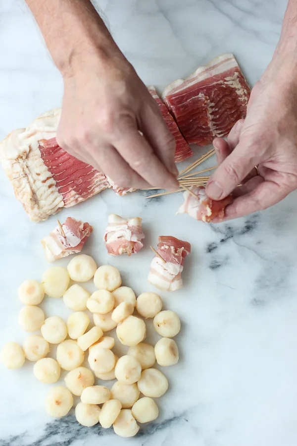 Demonstrating how to wrap the water chestnuts with bacon