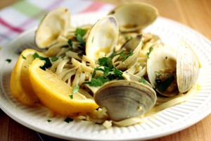 linguine and clams plated and garnished with parsley and lemon wedges