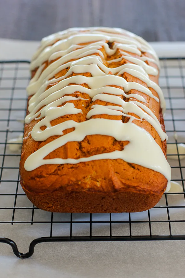 Finished pumpkin bread with cream cheese glaze on a cooling rack