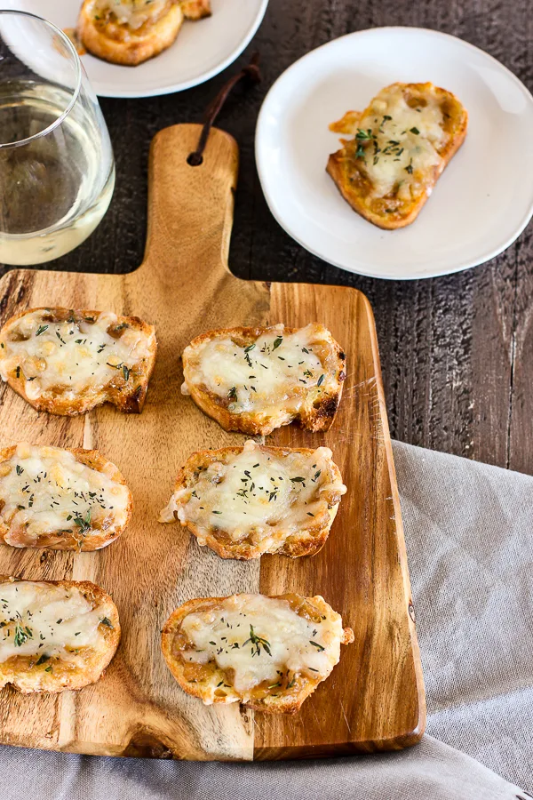 French onion cheese toasts served on a wooden board with white wine