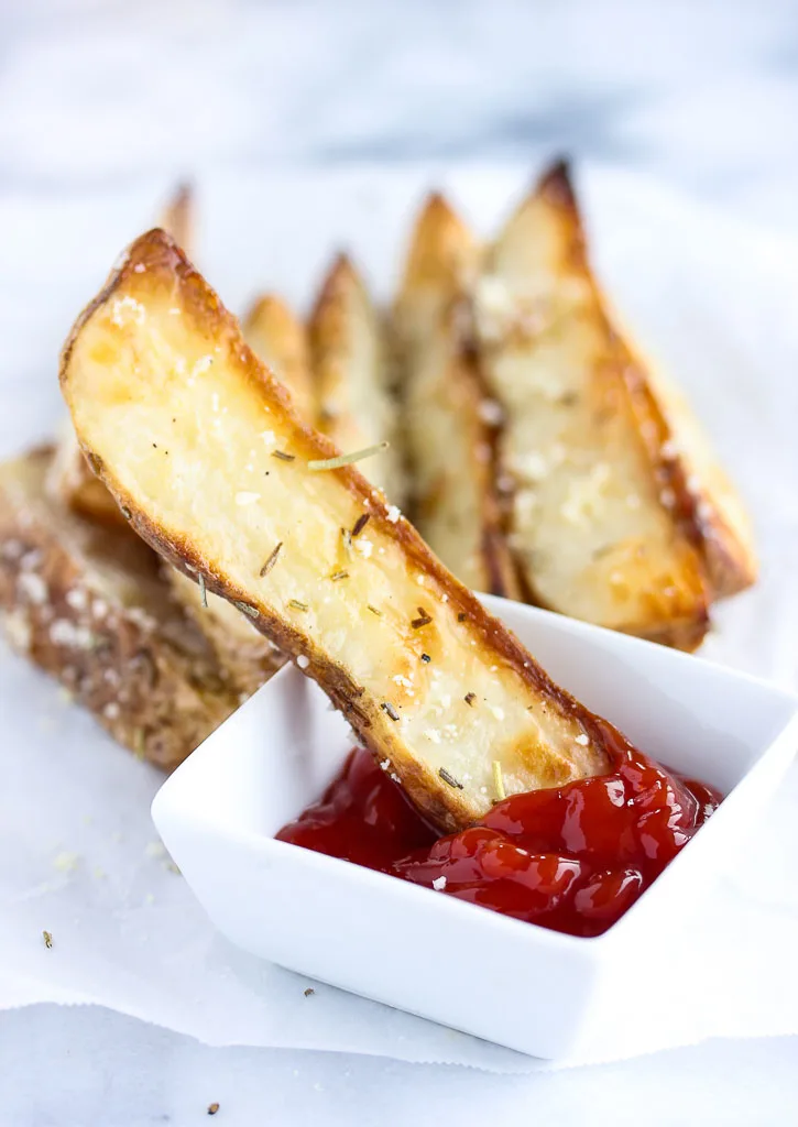 rosemary parmesan steak fry being dipped in ketchup