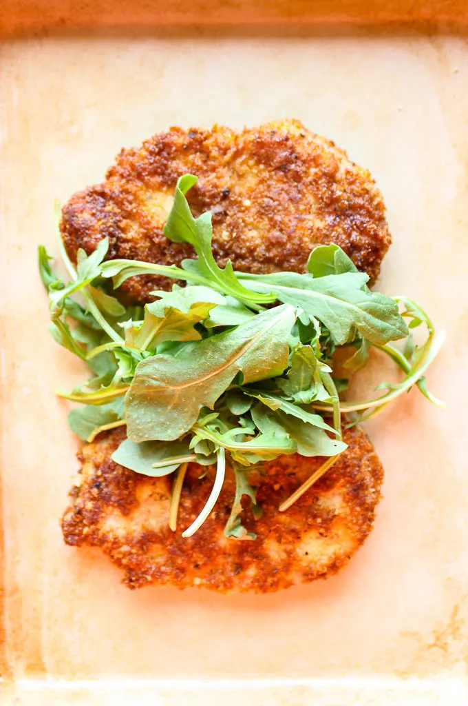 Overhead shot of finished pork milanese topped with arugula