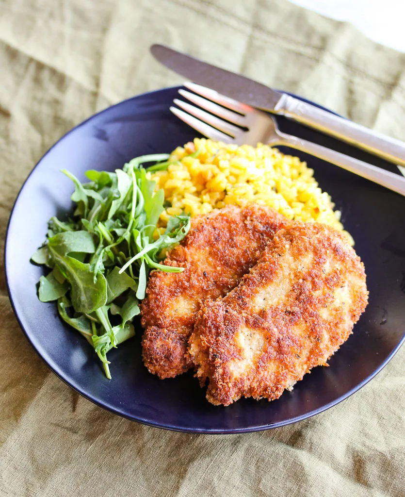 Overhead photo of plated pork milanese, risotto and arugula