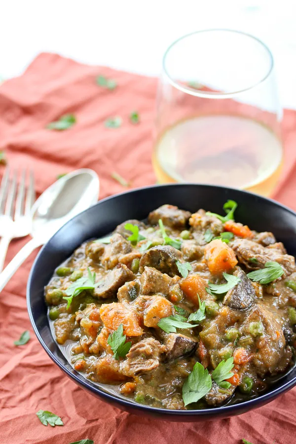 Lamb, Sweet Potato and Mushroom Stew served with a glass of white wine.