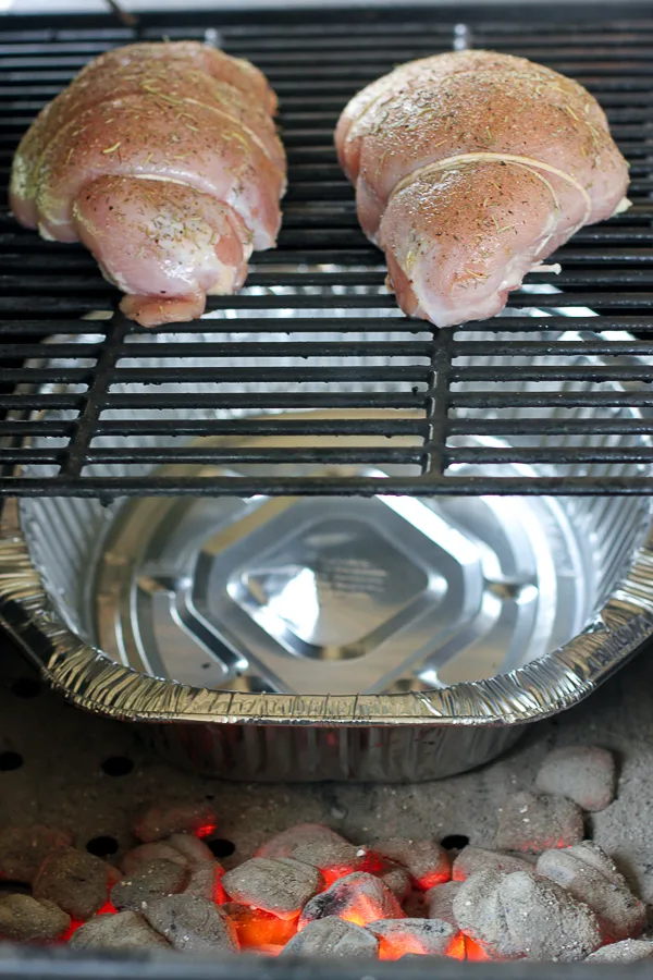Uncooked turkey on the grill illustrating how to position the charcoal around the drip pan