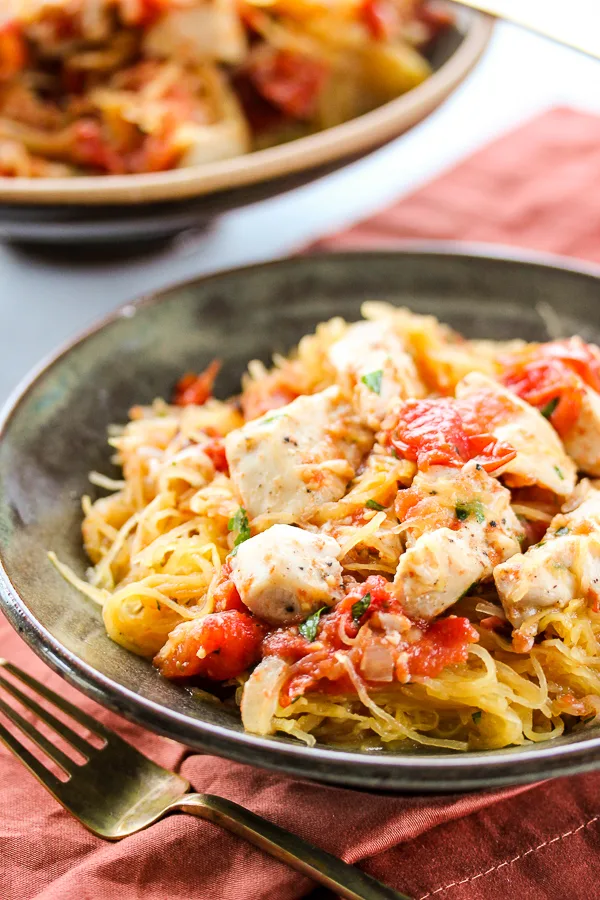 Roasted tomato and chicken sheet pan dinner over spaghetti squash is healthy, naturally gluten free and incredibly flavorful. Plus, it's so easy to prepare.