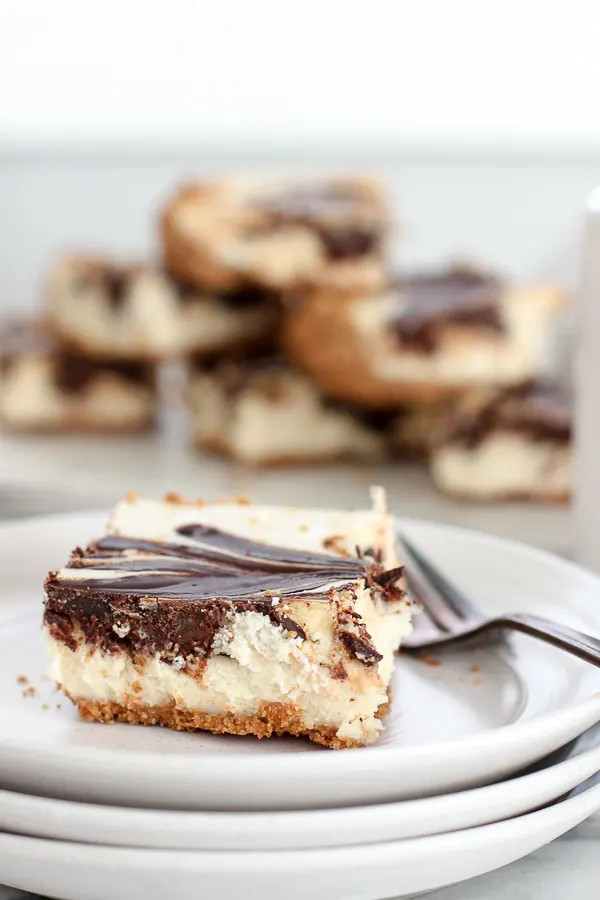 Chocolate swirl cheesecake bar plated with a serving plate of the bars in the background