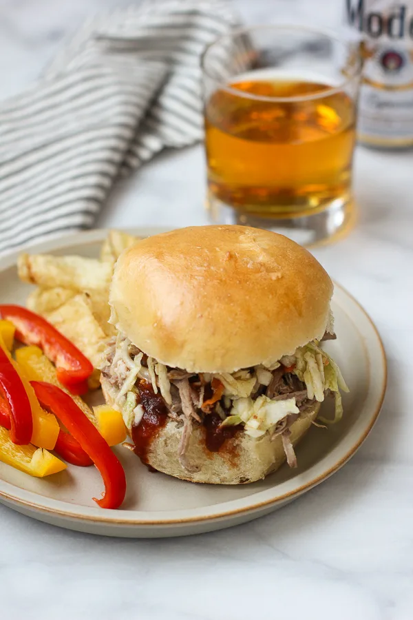 Pulled pork sandwich topped with coleslaw and barbecue sauce.