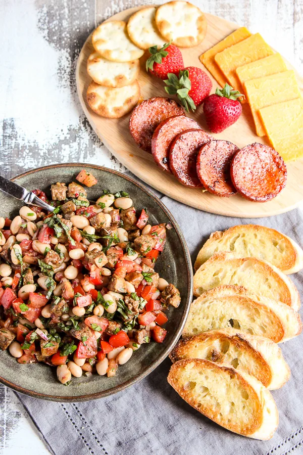 Italian sausage and white bean bruschetta plated and served with crostini along with sliced sausage, cheese and crackers