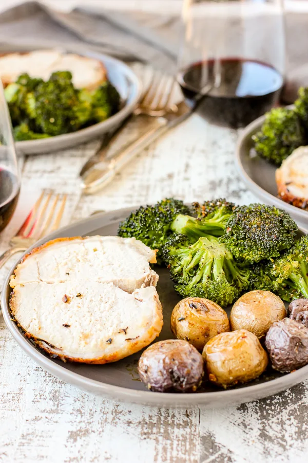 Sliced Pork and the roasted vegetables on served on dinner plates ready to eat.