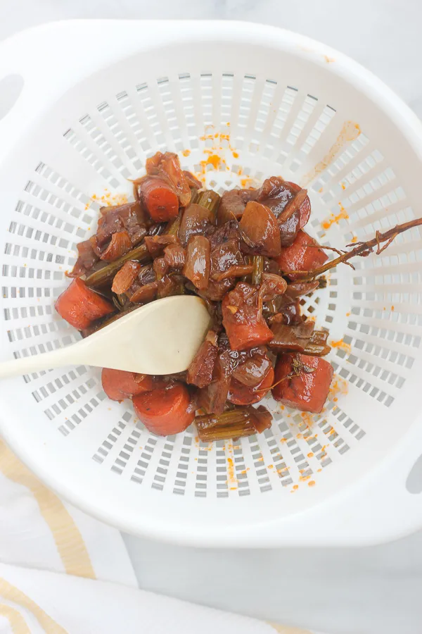 Pressing the liquid out of the vegetables in a strainer after cooking