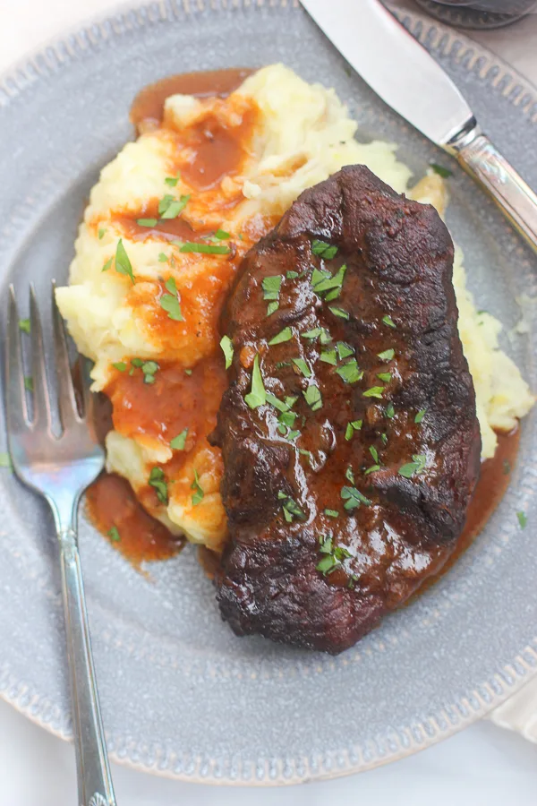 Close up overhead shot of the short ribs served over mashed potatoes and topped with the sauce