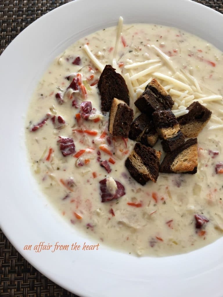 Cream of reuben soup served in a bowl and topped with croutons and shredded cheese