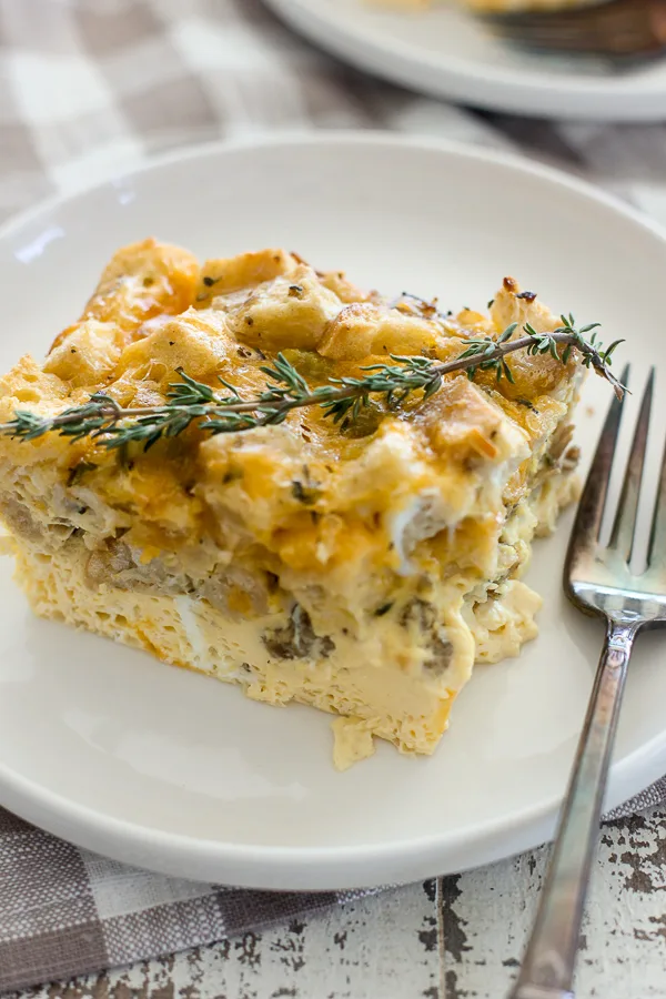 Close up photo of plated sourdough stuffing egg casserole garnished with a sprig of thyme