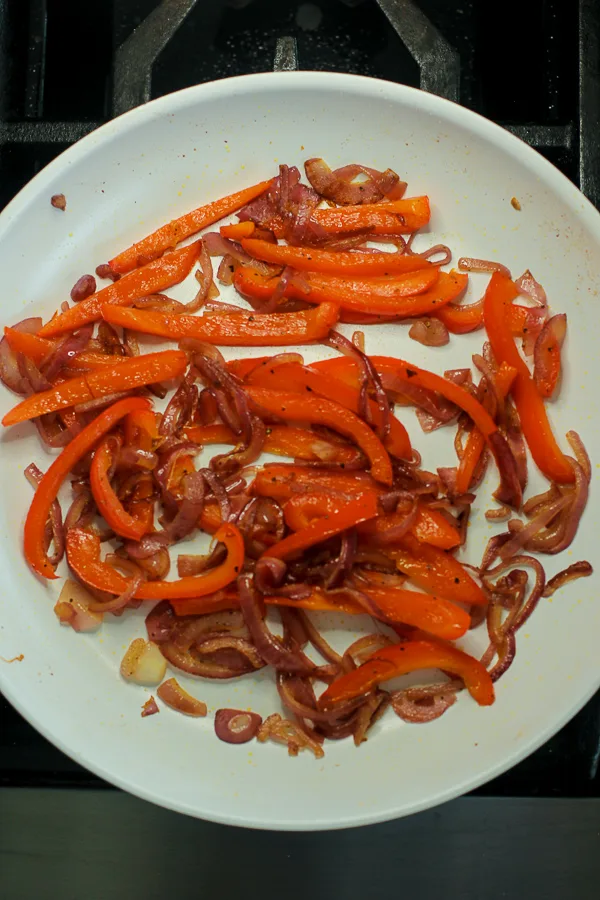 peppers and onions sautéing in a skillet