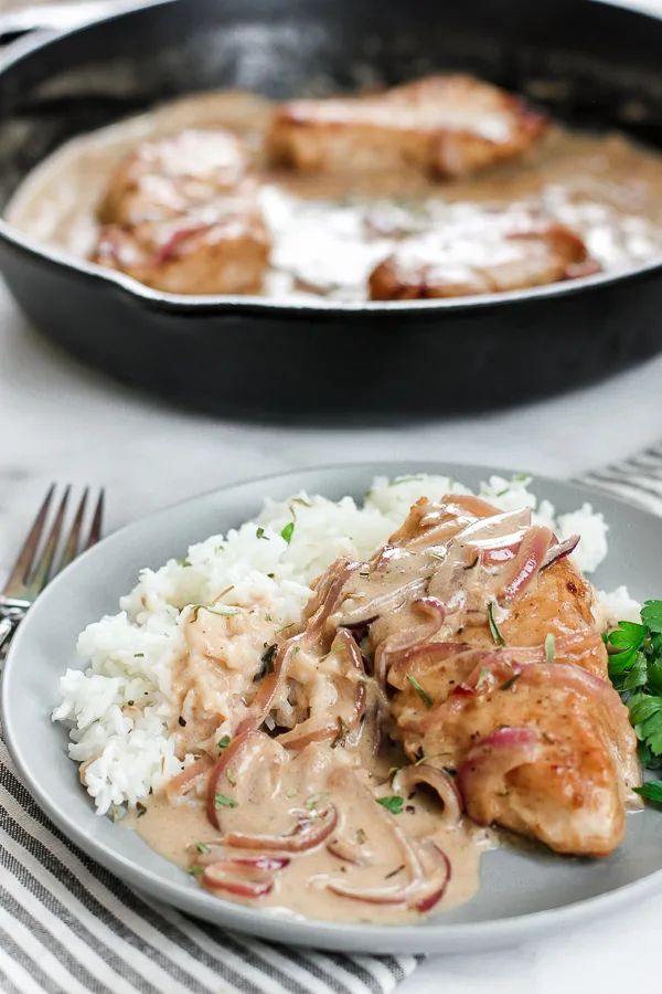 Skillet Chicken with Creamy Mustard Sauce served over rice with cast iron skillet in the background