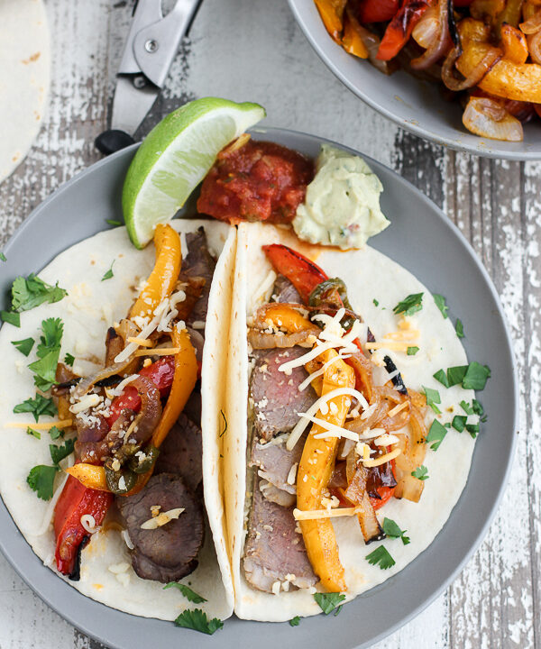 Overhead photo of fajitas serve on soft tortillas and topped with cheesed cilantro.
