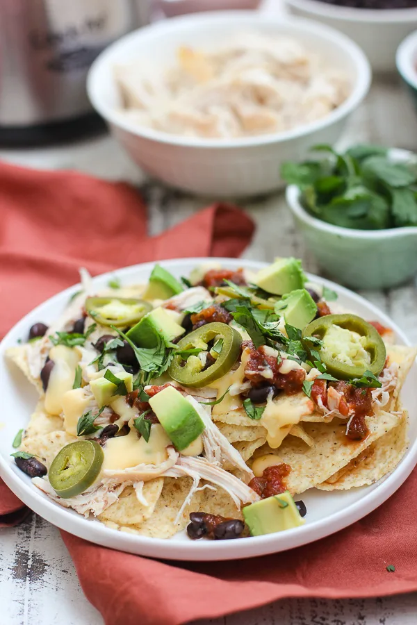 Plated chicken nachos with ingredients in the background
