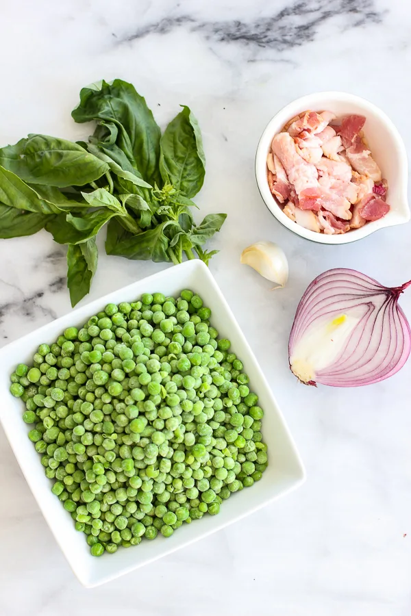 Showing ingredients needed to make recipe. Peas, bacon, garlic, onion and fresh basil.