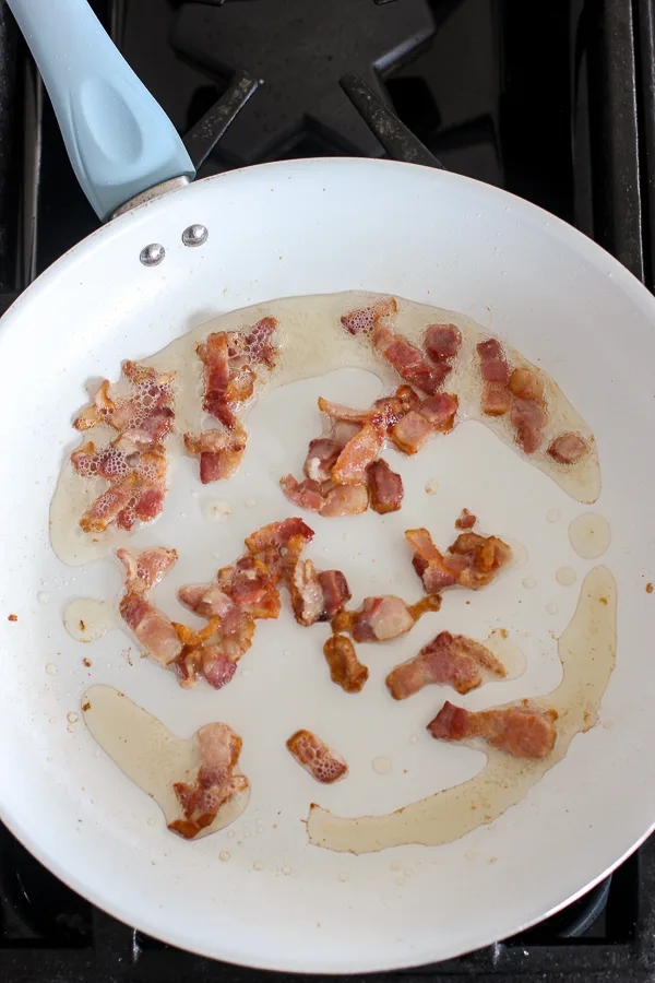 Bacon pieces being sautéed in a skillet