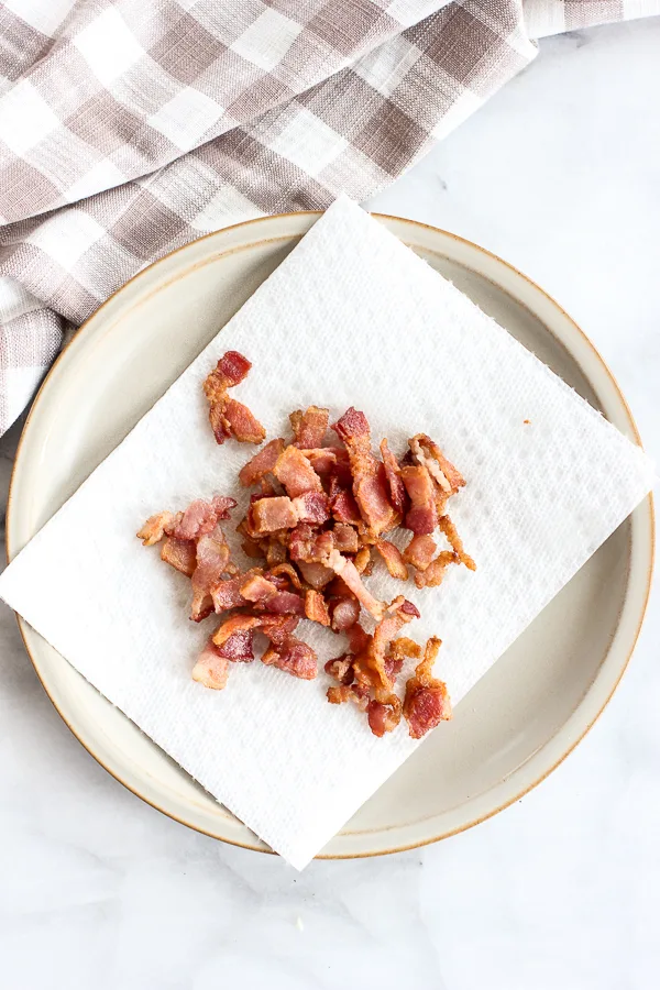 Cooked bacon bits being drained on a paper towel