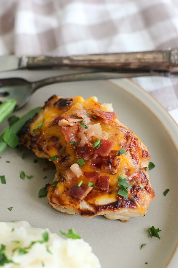 Close up photo of cheddar cheese ranch chicken thighs with bacon served on a plate.