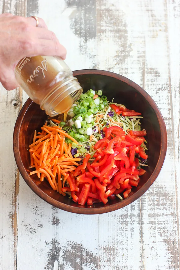 Pouring the dressing onto the vegetables in the salad bowl