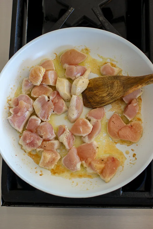 Sautéing diced chicken breast in a skillet