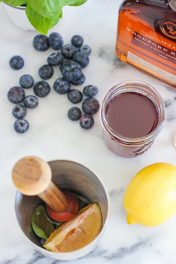 Demonstrating how to muddle the blueberries, lemon and simple syrup in a cocktail shaker with a wooden muddler.