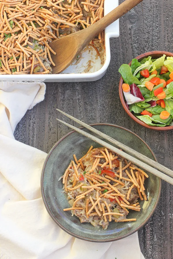 Overhead of chow mein casserole, along with a green salad and the baking dish