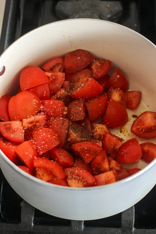 The tomatoes chopped, seasoned with salt and pepper ready to be cooked down