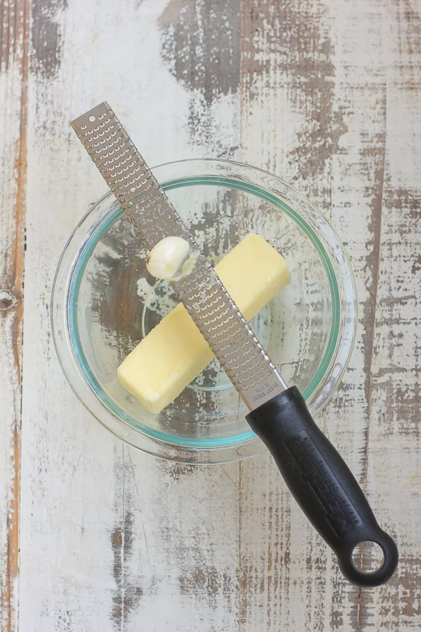 demonstrating how to grate garlic with a microplane grater.