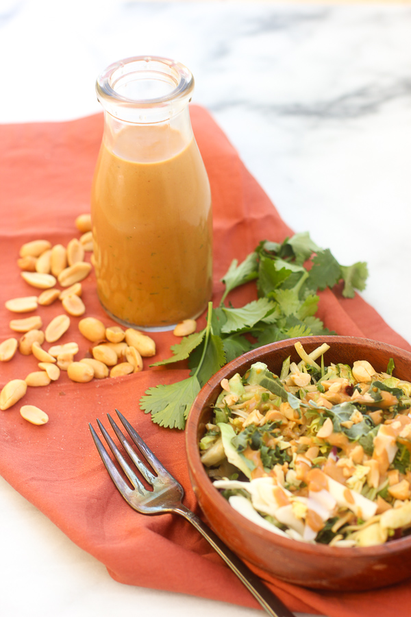 Thai peanut dressing in a bottle and an Thai salad dressed with it in a bowl